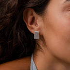 Close-up of a woman's ear wearing Ribbed Earrings in White Gold, featuring a rectangular shape and textured column design, highlighting contemporary jewelry style.