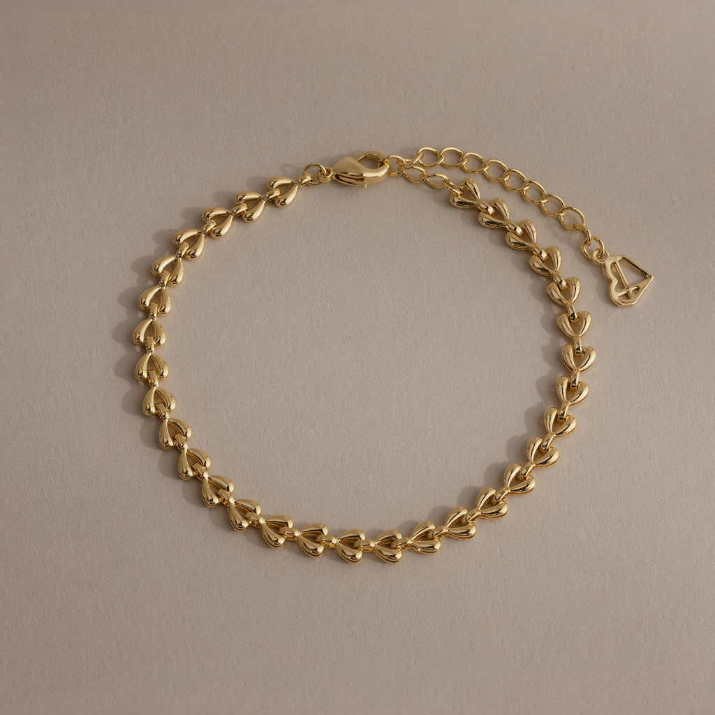 Tiny Link Heart Bracelet in gold featuring interlocking polished heart links on a neutral background.