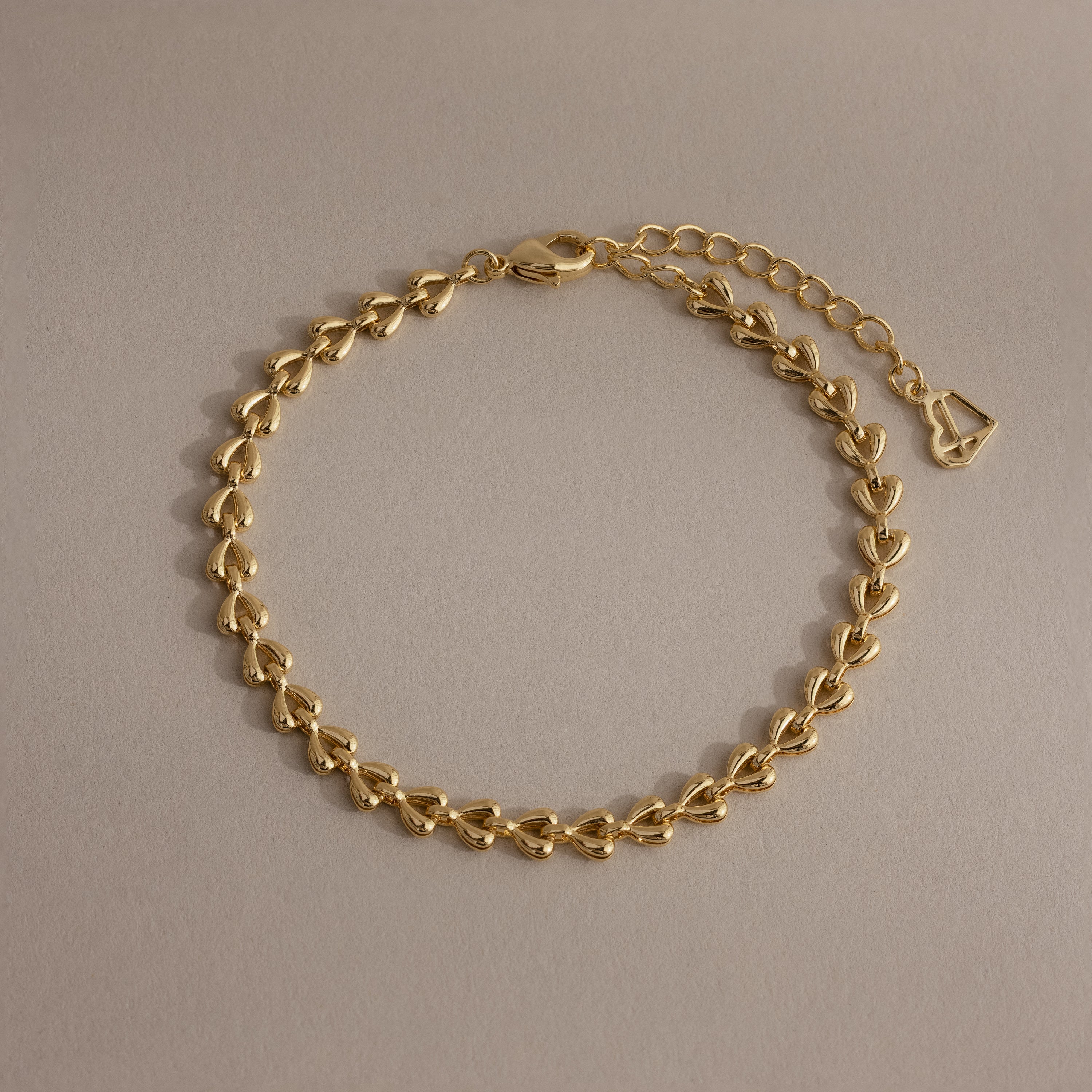 Tiny Link Heart Bracelet in gold featuring interlocking polished heart links on a neutral background.