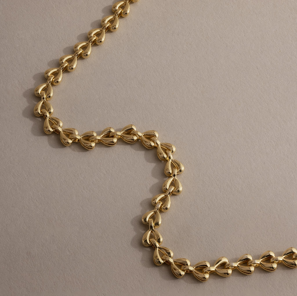 Close-up of gold Tiny Link Heart Bracelet showing polished interlocking heart details.