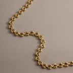 Close-up of gold Tiny Link Heart Bracelet showing polished interlocking heart details.