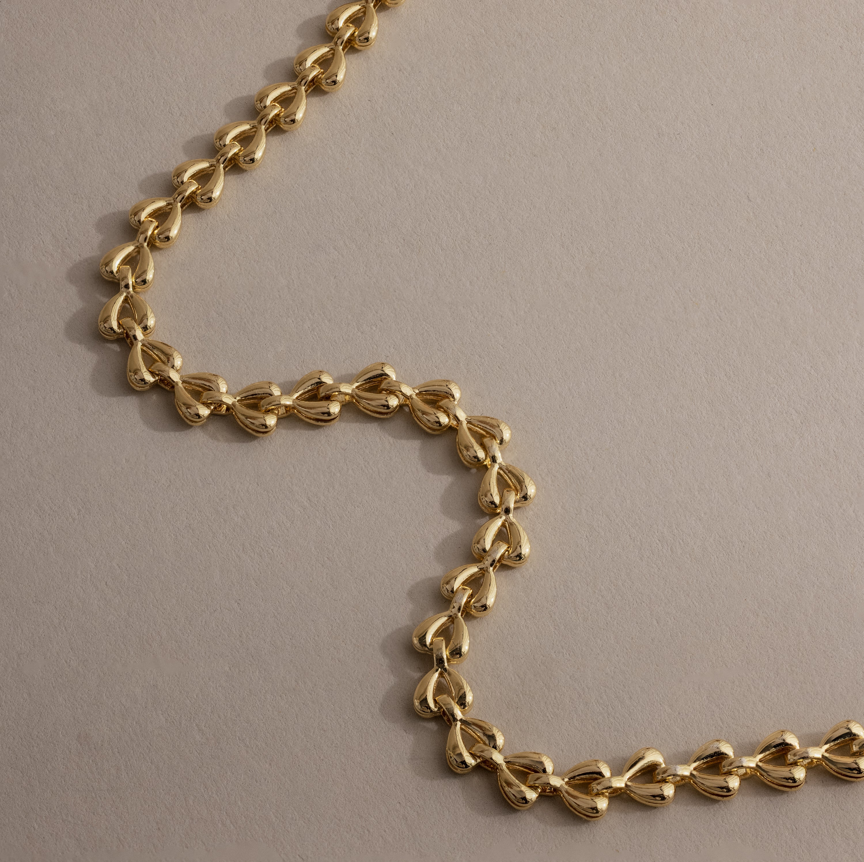 Close-up of gold Tiny Link Heart Bracelet showing polished interlocking heart details.
