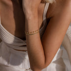 Model wearing the Tiny Link Heart Bracelet in gold, stacked with a dainty pearl eternity bracelet.