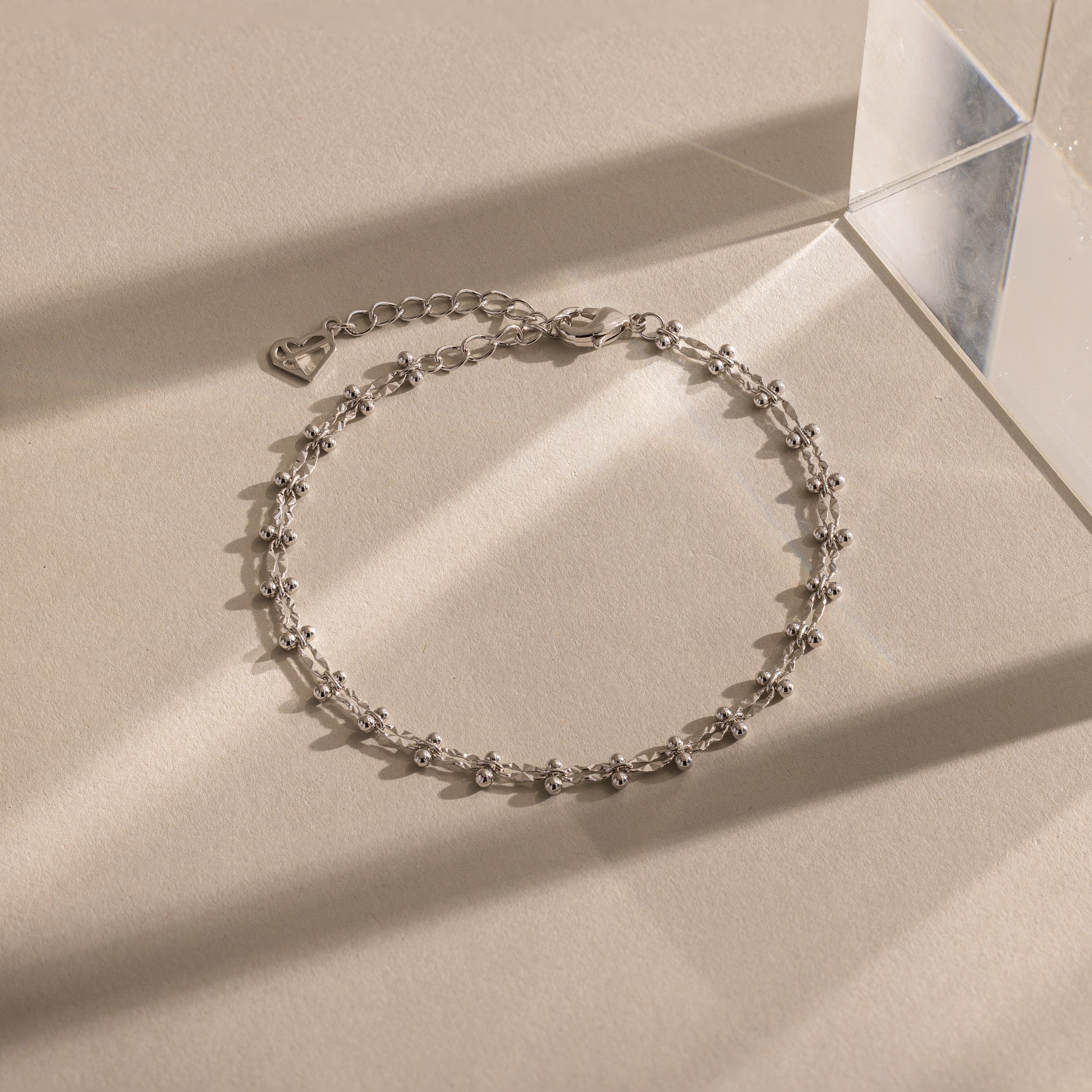 Close-up of a silver Beaded Mirror Chain Bracelet displayed on a neutral surface.