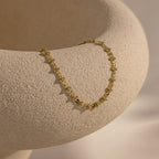 Gold Dainty Mirror Chain Bracelet draped over a textured ceramic surface.