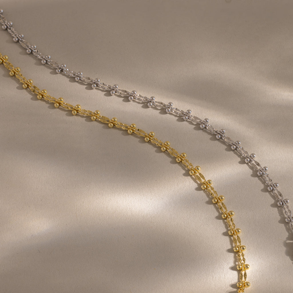 Close-up of two Dainty Mirror Chain Bracelets, one gold and one silver.