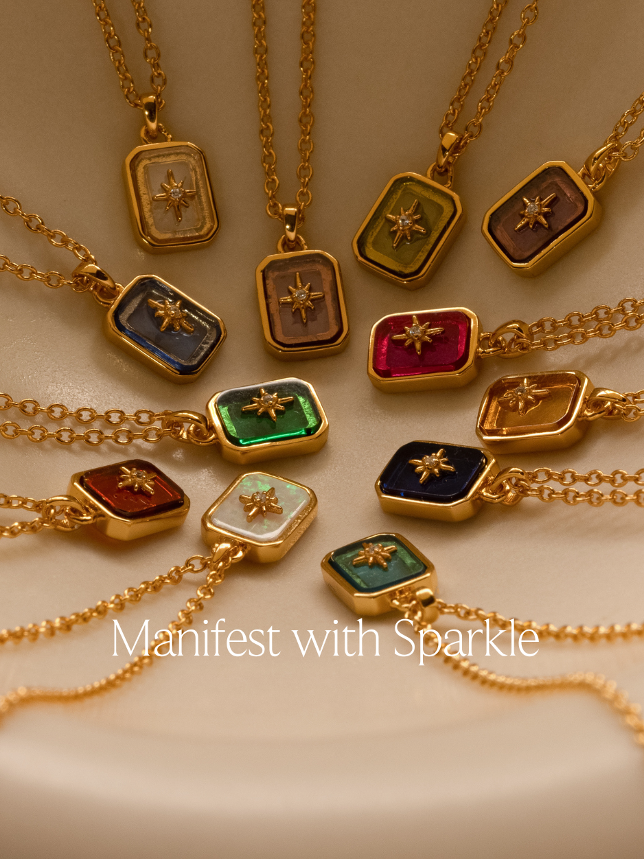 A banner with text "manifest with sparkle" featuring a flatlay of birthstone pendant necklaces with a north star gemstone.