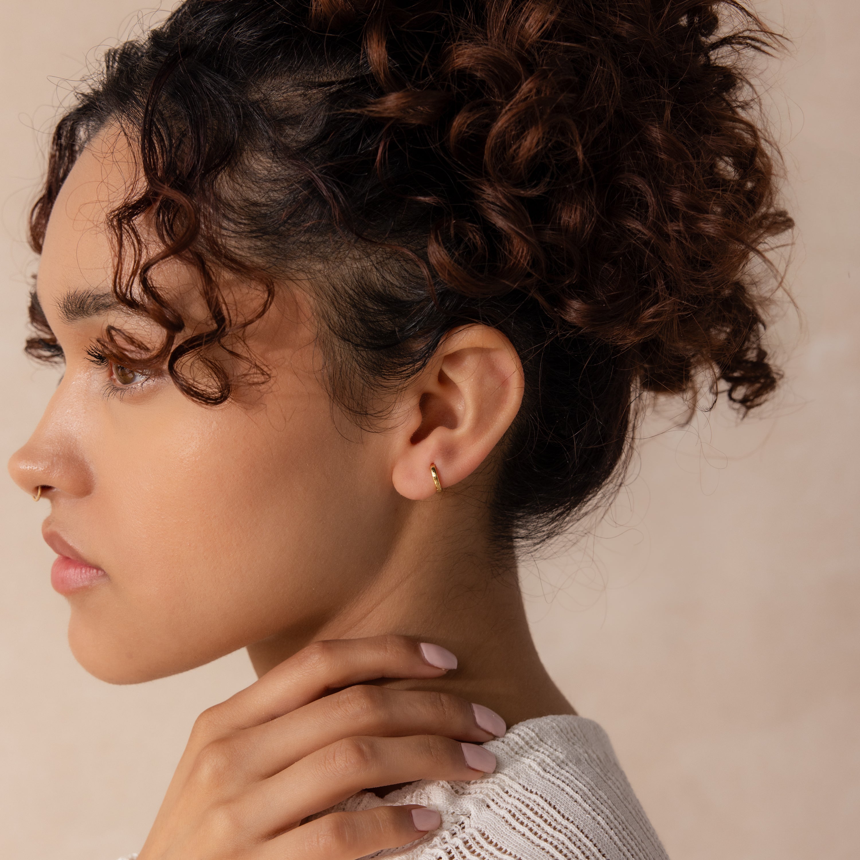 Model wearing a single 7mm Mini Classic Huggie Hoop Earring in gold, styled with a soft updo and neutral makeup.