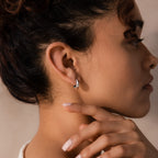Model wearing a single silver oval-shaped huggie earring against a neutral background.