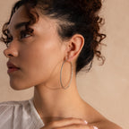 Model wearing silver hoop earrings with a sleek, textured design that reflects light beautifully.