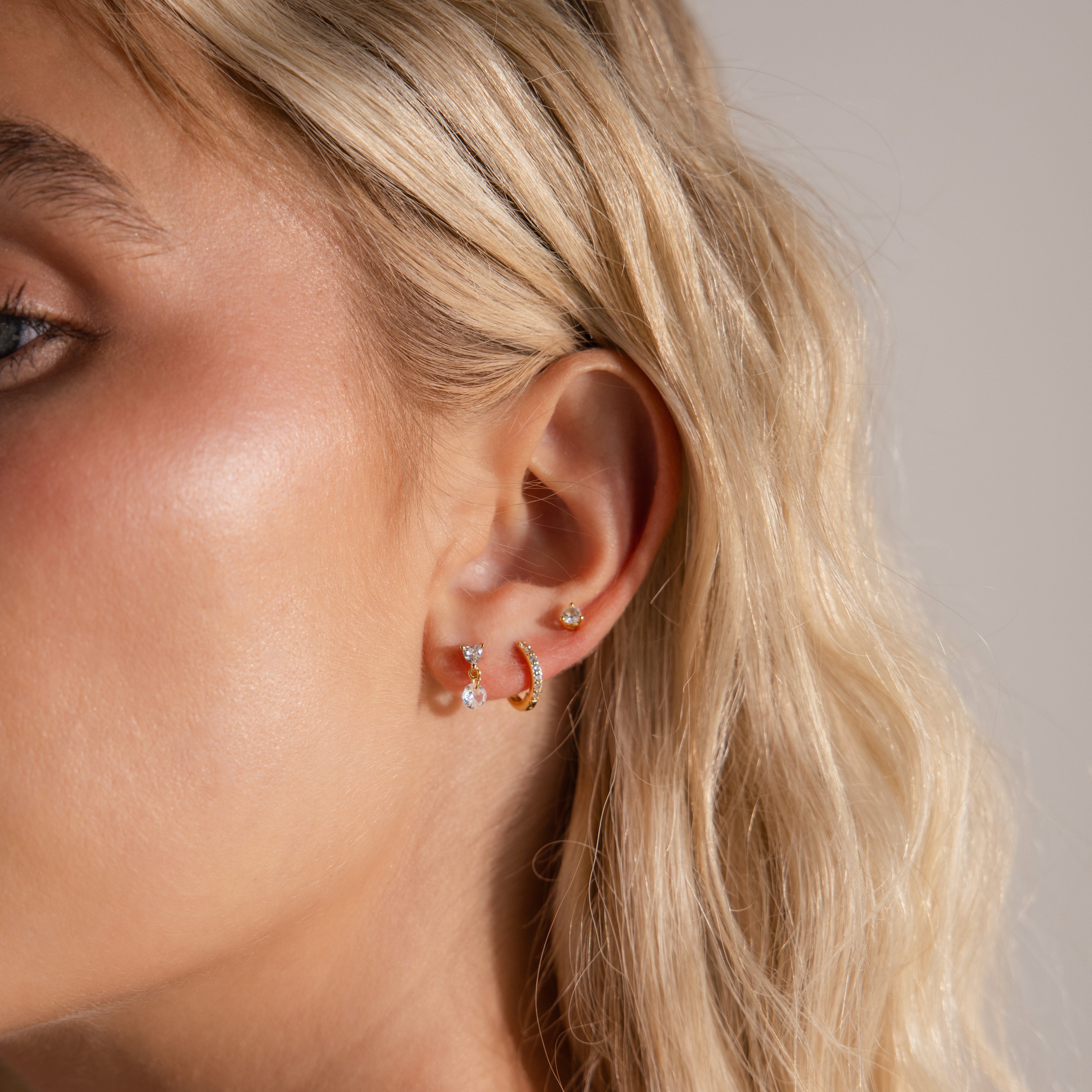 Model wearing dainty Heart Drop Flatback Studs in 18K Gold, stacked with a pave gold huggie hoop and classic diamond stud.