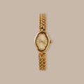Clover Link Timepiece: Gold-tone watch with petite oval dial, crystal accents, and polished link bracelet.