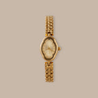 Clover Link Timepiece: Gold-tone watch with petite oval dial, crystal accents, and polished link bracelet.