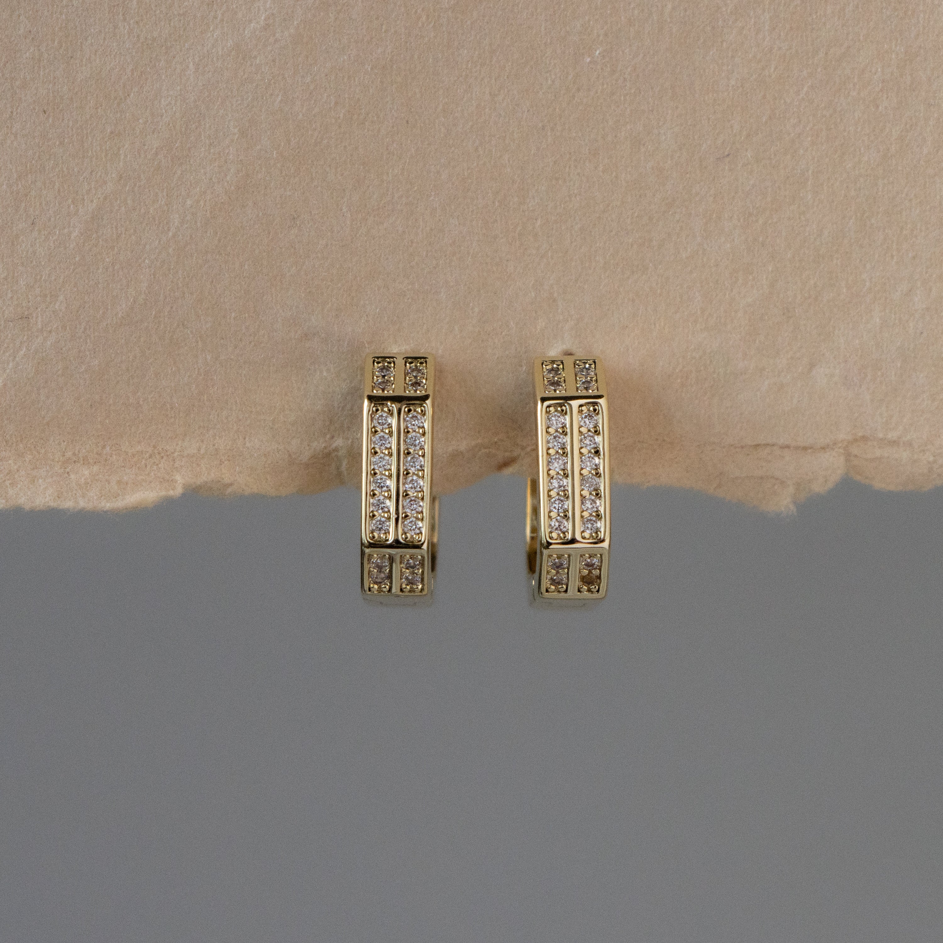 Double Pave Octagonal Hoops—gold earrings with octagonal shapes and rows of shimmering gems—are displayed on a tan and gray background.