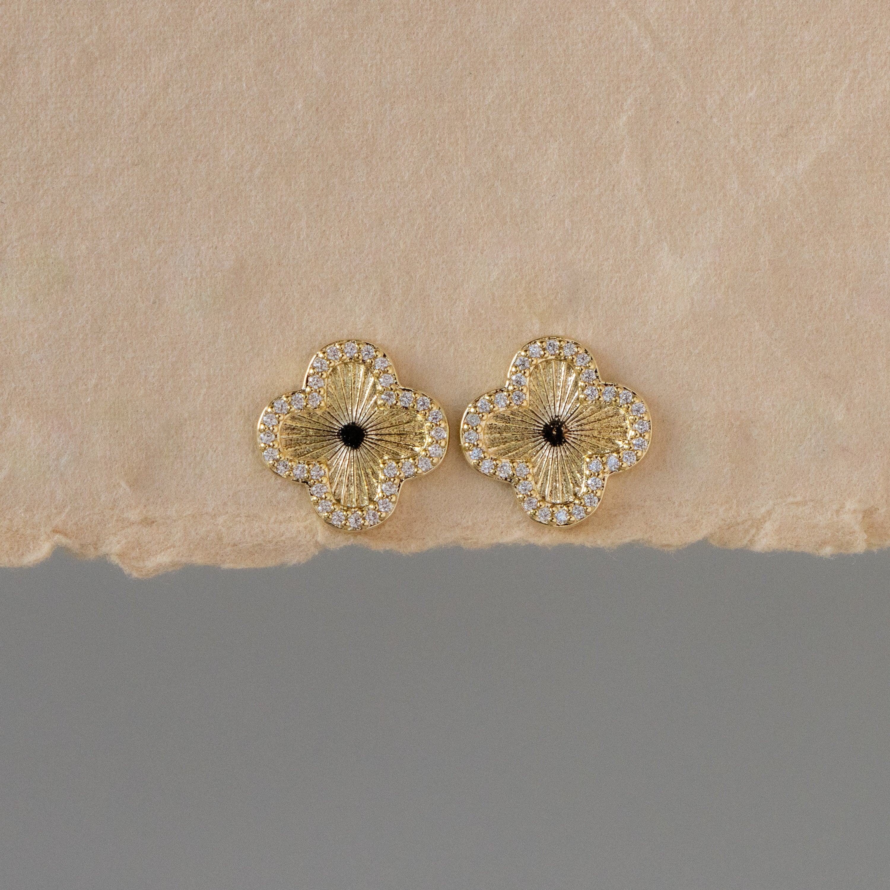 Fluted Pave Flower Studs with diamond borders are shown on a textured beige surface.