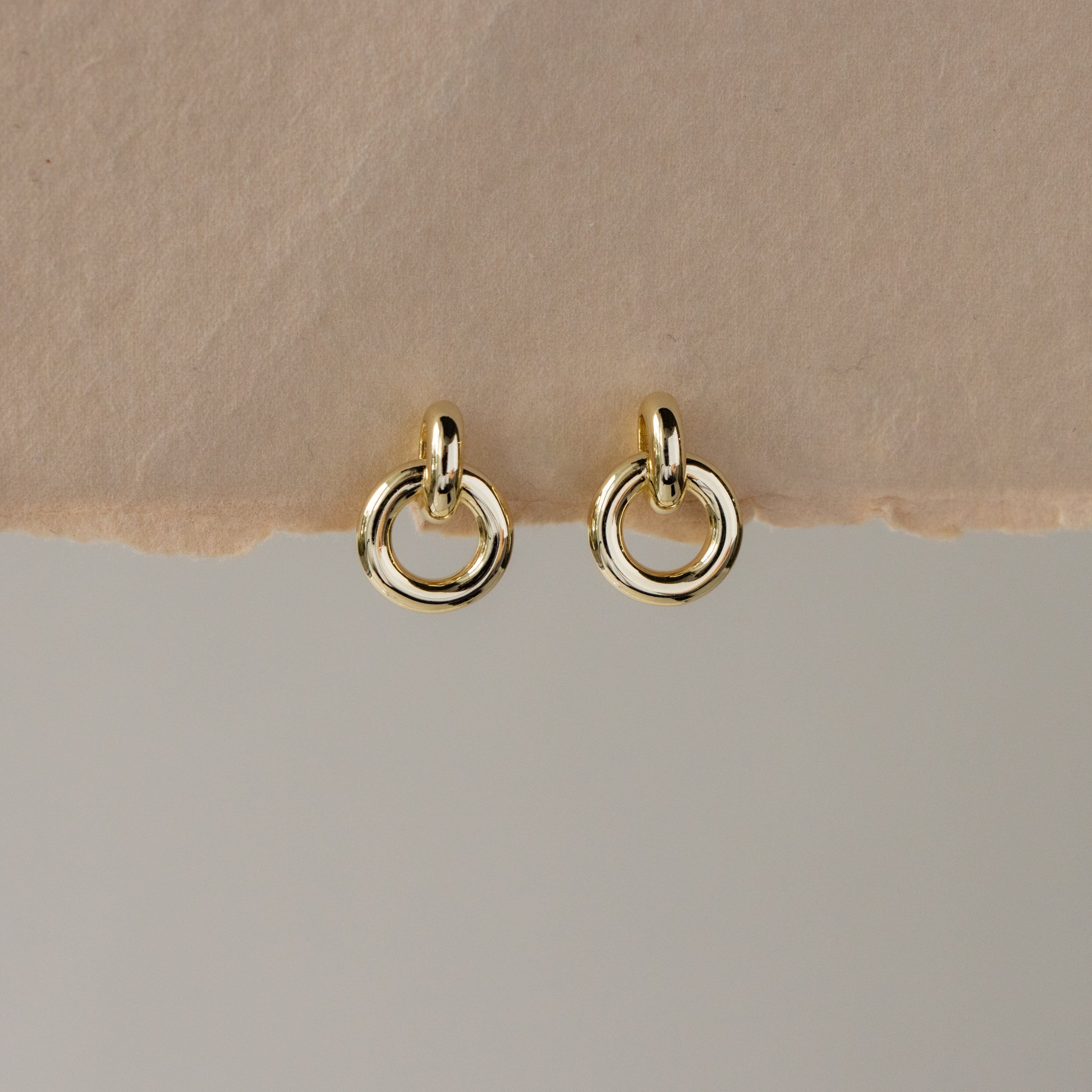 Round Link Drop Studs displayed on a light beige textured surface.