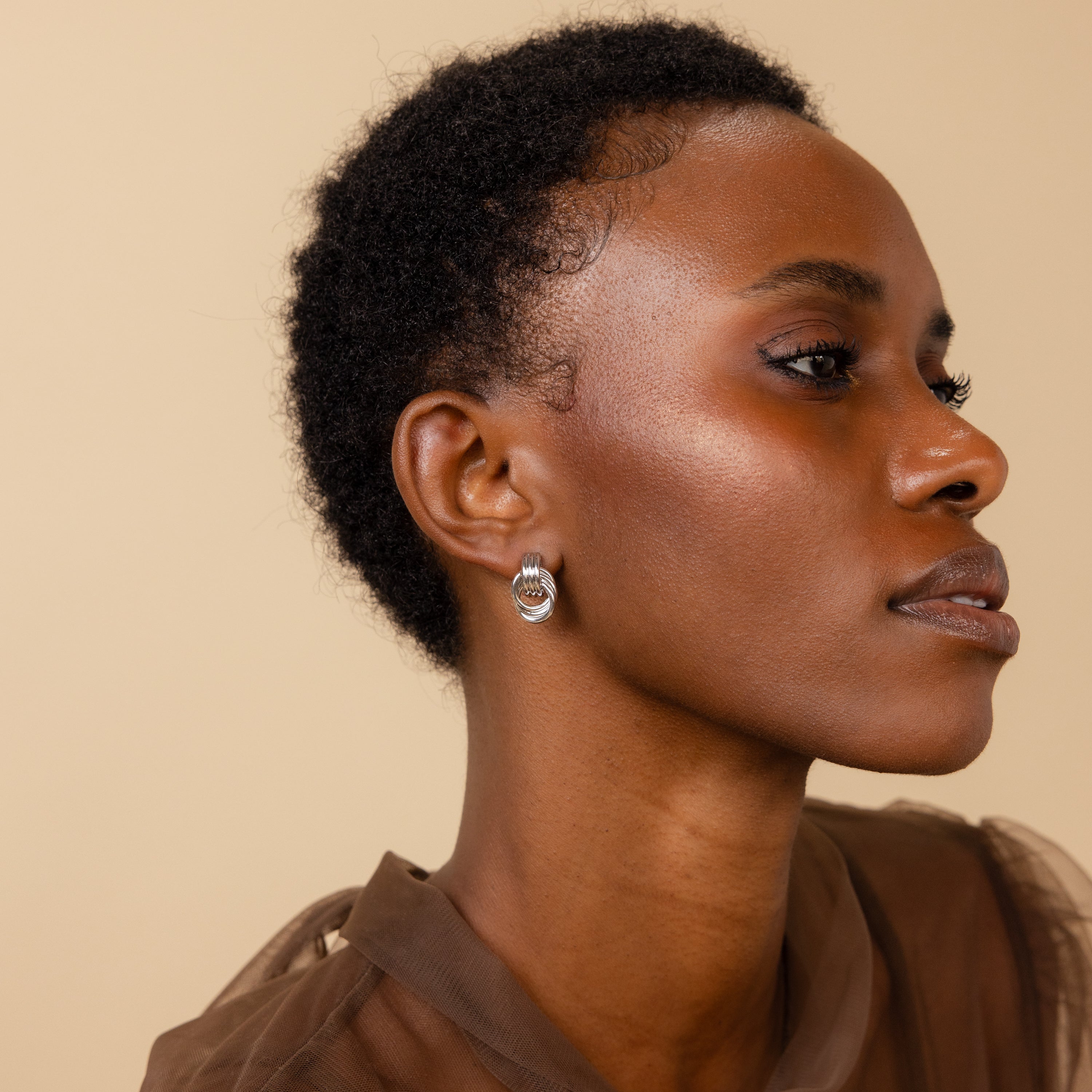 Side profile of a model wearing silver Mini Triple Knot Earrings.