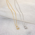 The Sage Diamond Necklace in Silver, featuring a delicate rectangular pendant, exudes timeless elegance against a light fabric background.