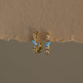 Opal Diamond Cluster Link Hoops featuring opal and clear stones, displayed on a textured beige surface.