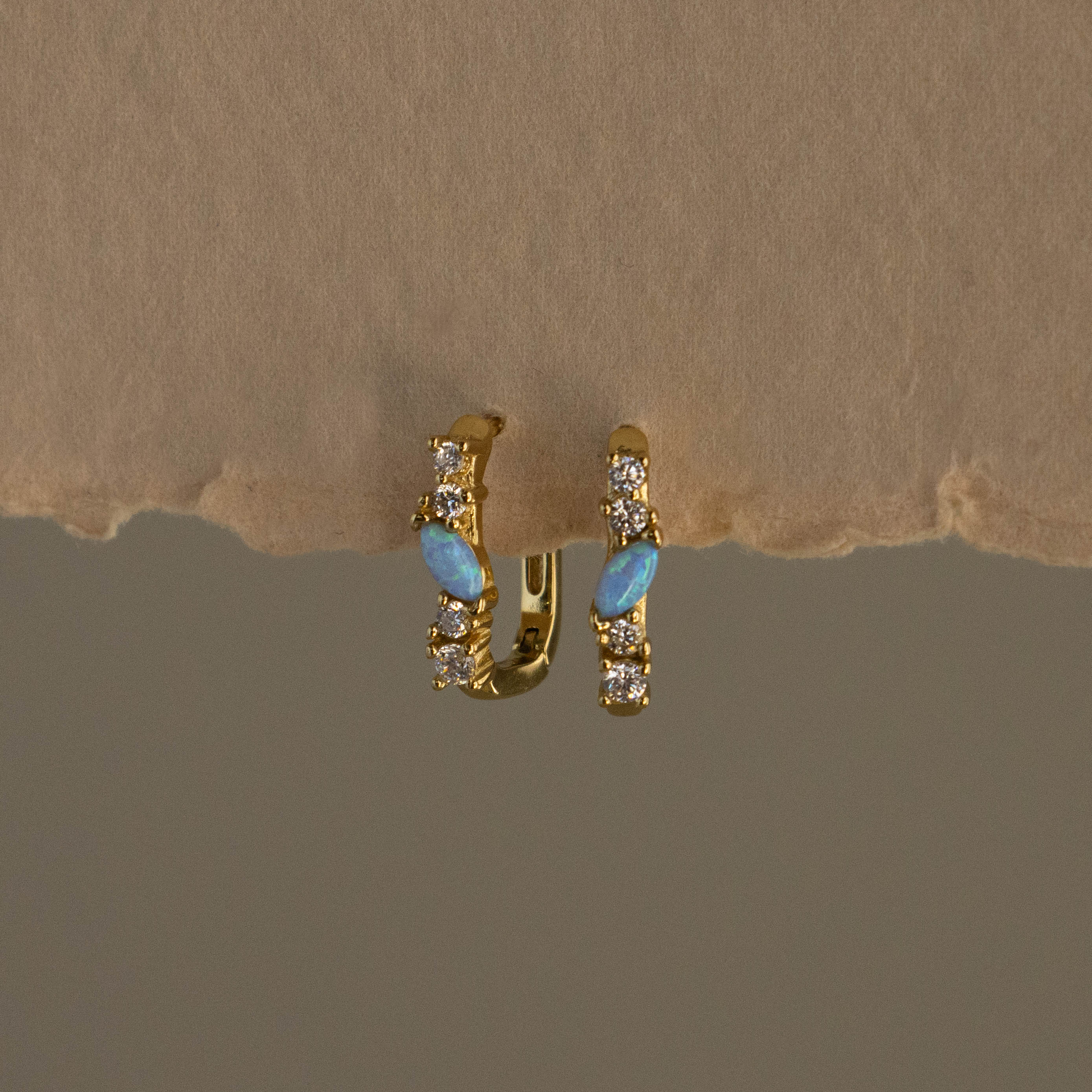 Opal Diamond Cluster Link Hoops featuring opal and clear stones, displayed on a textured beige surface.