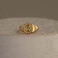 Topaz  Diamond Heritage Signet Ring featuring an oval yellow topaz surrounded by small diamonds, displayed on a textured stone surface.