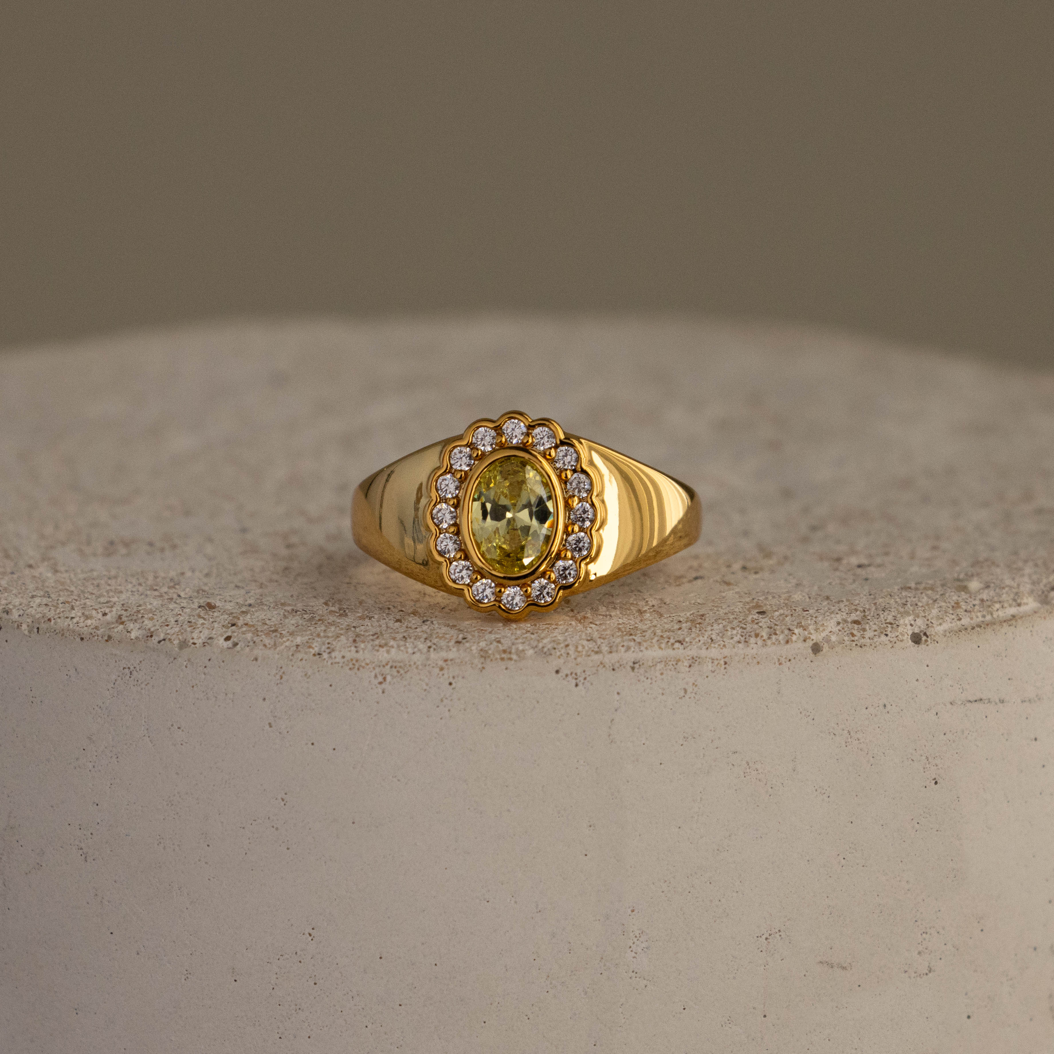 Topaz  Diamond Heritage Signet Ring featuring an oval yellow topaz surrounded by small diamonds, displayed on a textured stone surface.