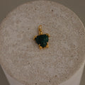 Malachite Sea Turtle Charm with a green stone shell, shown on a round textured beige surface.