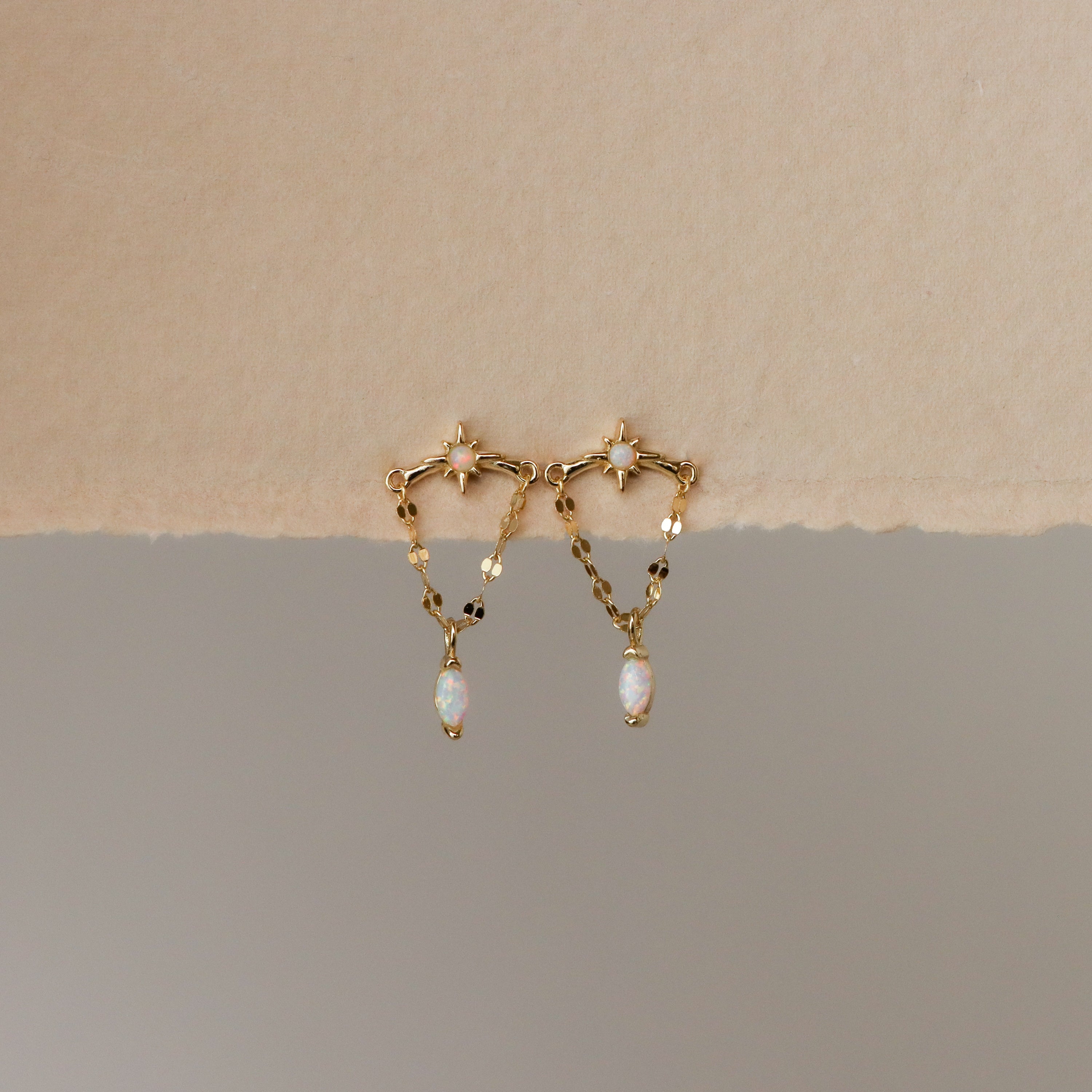 Marquise Opal Star Chain Studs featuring opal stones and delicate chains, showcased against a beige and gray background.