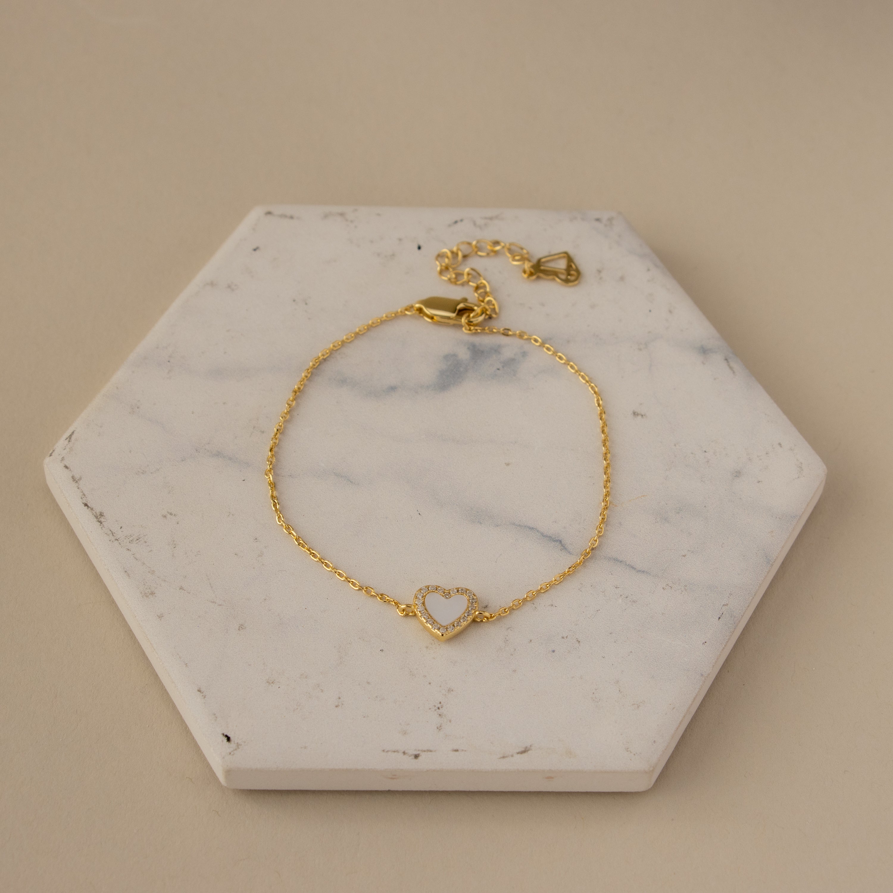 Mother of Pearl Pave Heart Bracelet displayed on a white hexagonal marble slab.