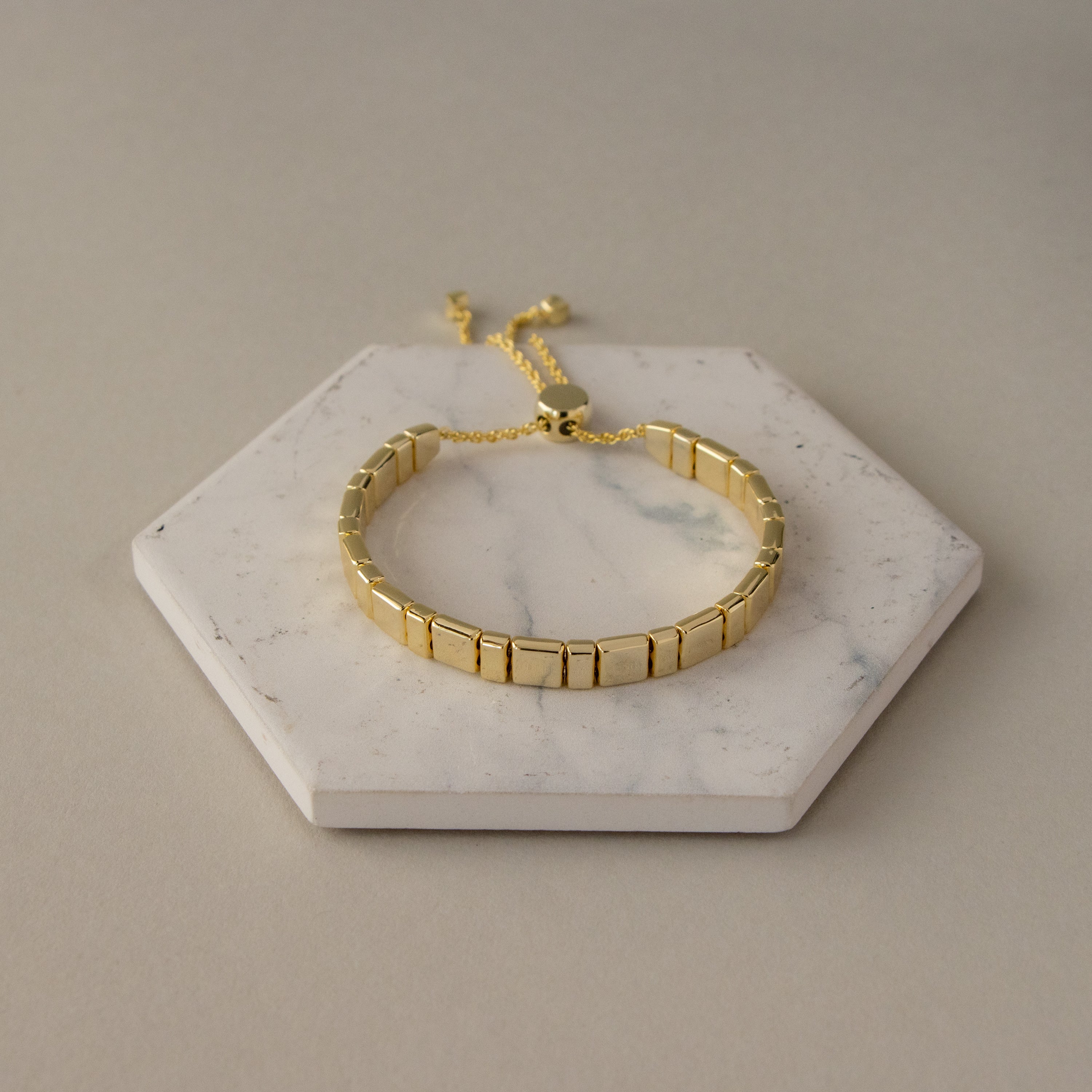Square Link Slider Bracelet displayed on a marble hexagon tray with a neutral background.
