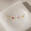 Gold bracelet with letter B, red heart, pink gem, and gold disc on a white square—perfect for pairing with the Dainty Space Charm Necklace or other customizable charm necklace styles.
