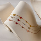 The Dainty Space Charm Necklace in Rose Gold gleams on a sculpted beige surface—an elegant piece, ideal for pairing with your favorite charm bracelets or other customizable jewelry.