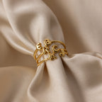 Gold stackable dainty initial rings featuring 3D bubble-style letters E, B, R, C, K, and J displayed on soft champagne satin fabric.
