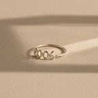 A silver “2006” Bubble Numbers Ring on a beige background. The ring has rounded bubble numbers with a smooth and shiny finish.