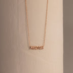 Dainty rose gold bubble name plate necklace with the name Micah, displayed against a neutral background.