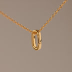 Multipurpose Charm Hoop Clasp Set in 18K Gold features a gold chain necklace with an oval pendant and a versatile charm hoop clasp, ideal for bracelet stacking, shown against a plain beige background.