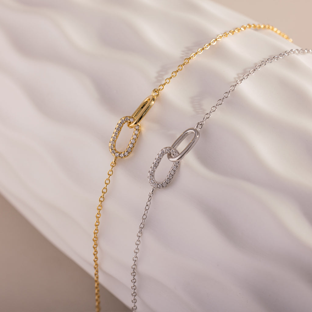 The Pave Linked Pendant Bracelet features interlocking links and oval, crystal-studded accents showcased on a white textured background.