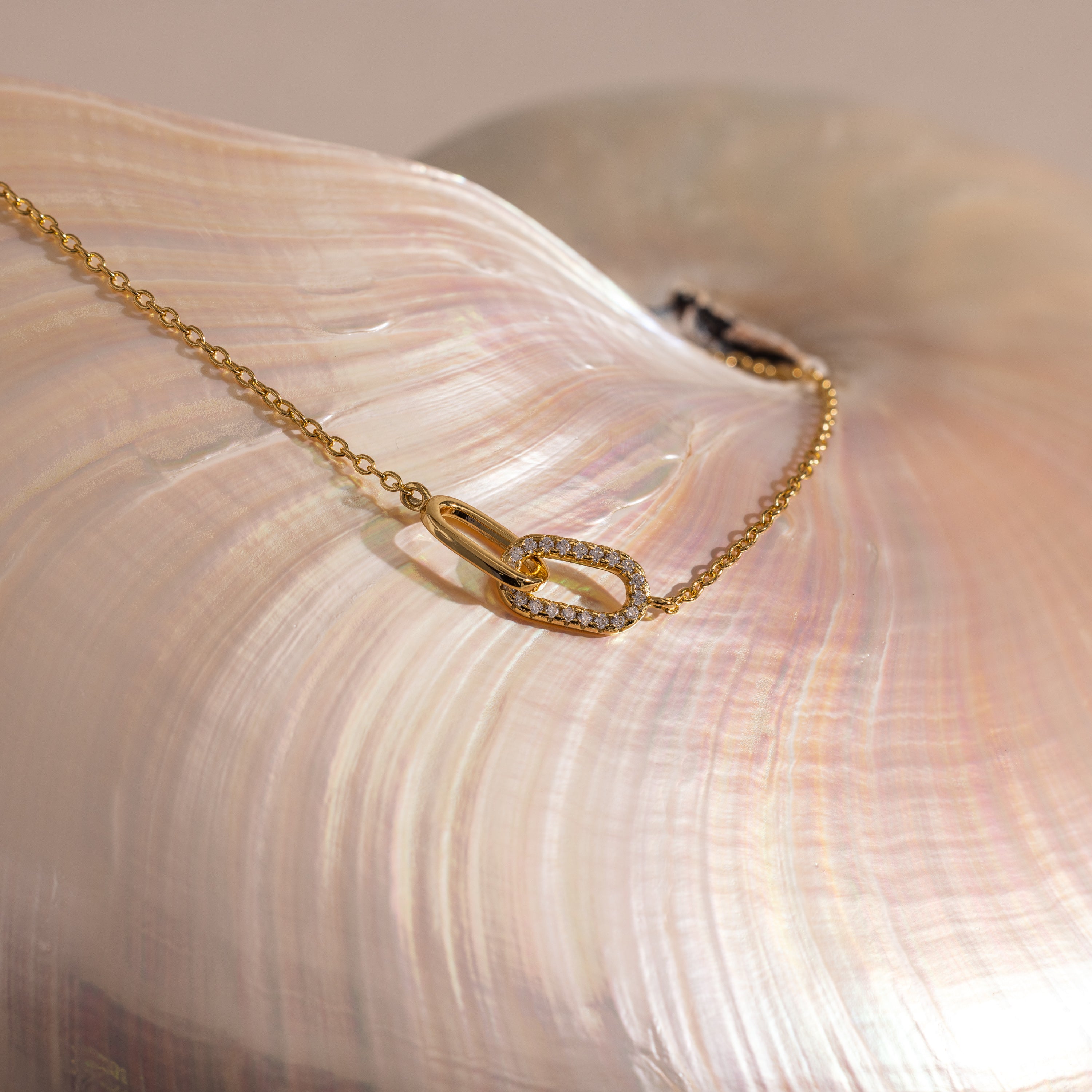 Pave Linked Pendant Bracelet in 18K Gold featuring interlocking links and a small diamond-studded pendant, displayed on a shiny seashell.