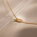 Close-up of a two gold interlocking pave diamond links charms, one circle and one oval link, on a dainty cable chain bracelet.