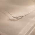 Close-up of a dainty silver chain bracelet featuring two interlocking links charms, one circle and one oval link.
