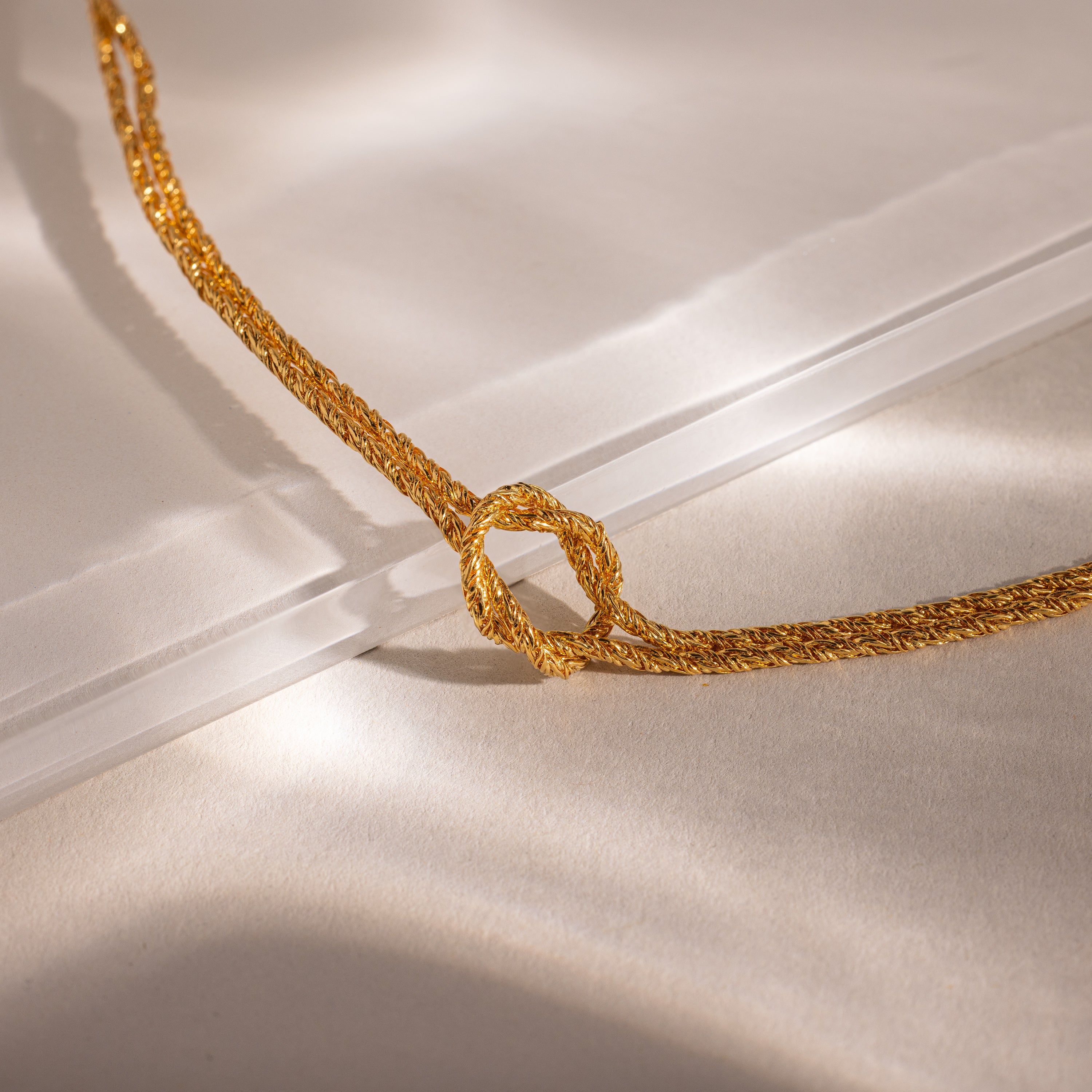 Close-up of the Rope Knot Chain Bracelet in gold with a center knot detail, displayed against a neutral background.