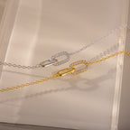 The Pave Linked Pendant Bracelet features interlocking links adorned with sparkling stones, showcasing its gem-encrusted elegance on a beige surface.