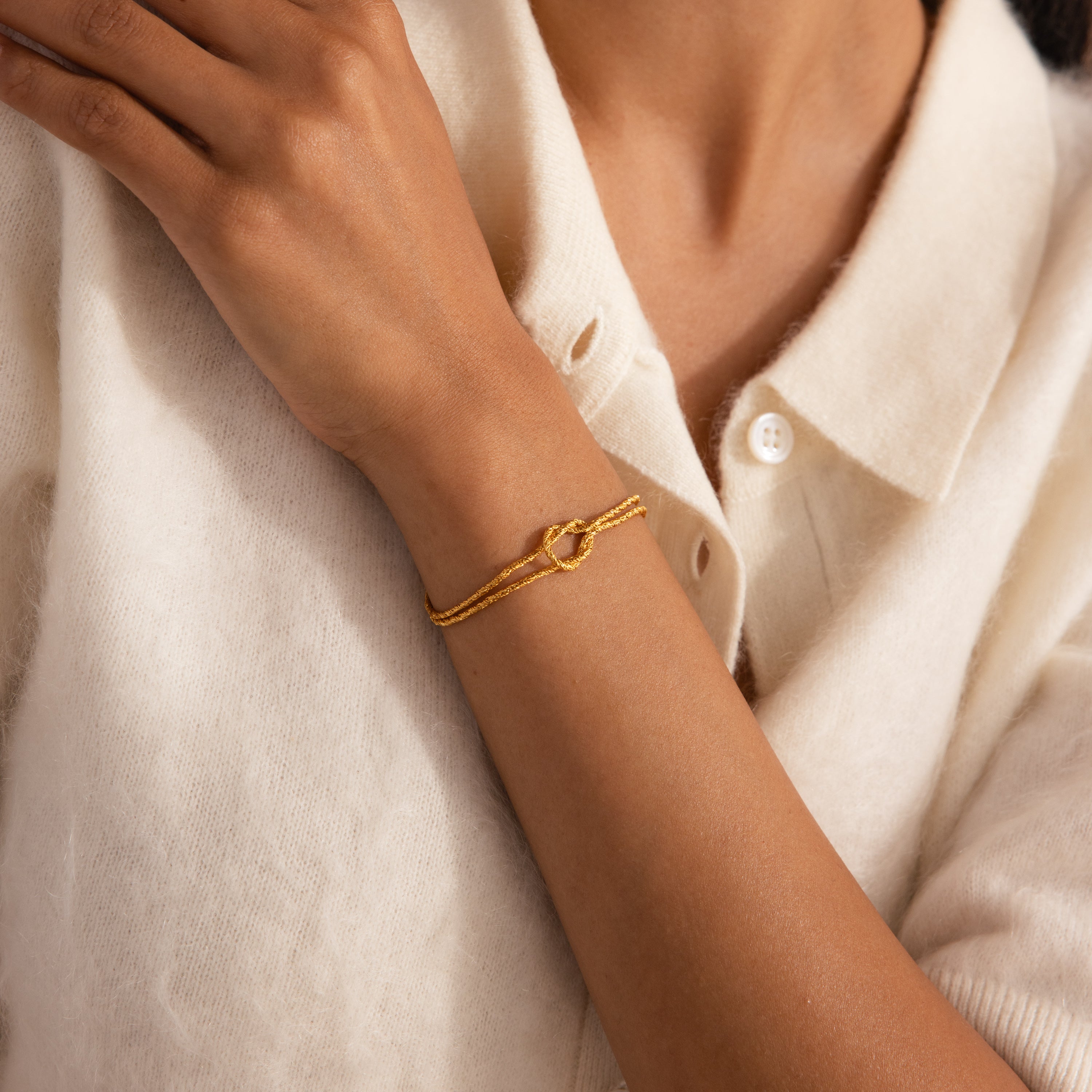 Model wearing the Rope Knot Chain Bracelet in gold with a center knot detail and duo chain design.