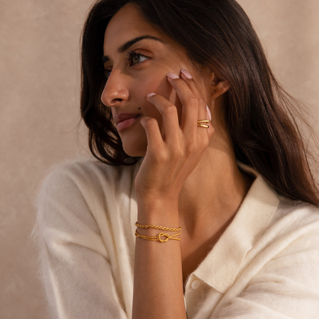 Model wearing the Rope Knot Chain Bracelet in gold, styled with a matching gold rope chain bracelet and gold duo band ring.