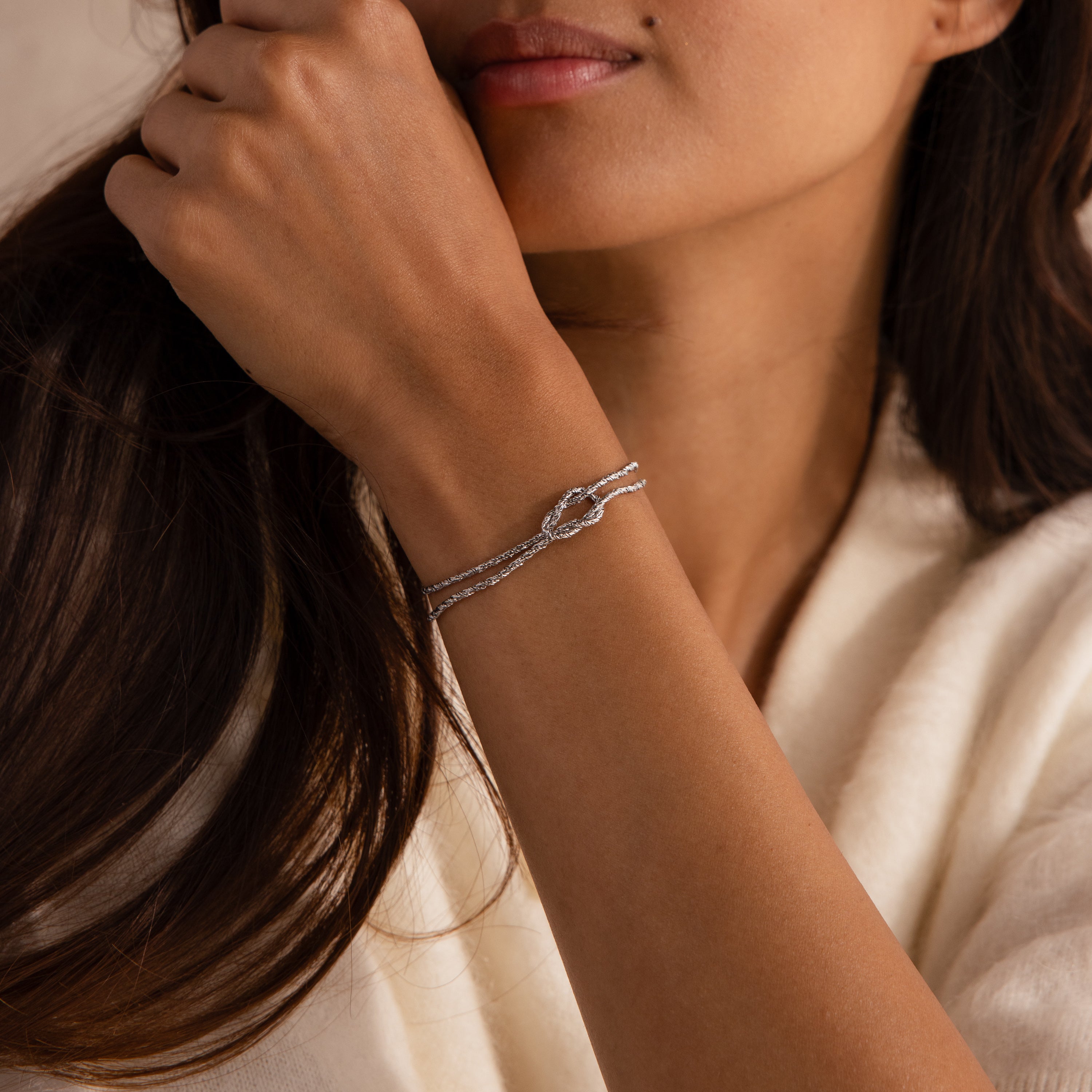 Model wearing the Rope Knot Chain Bracelet in silver with a center knot detail and duo chain design.