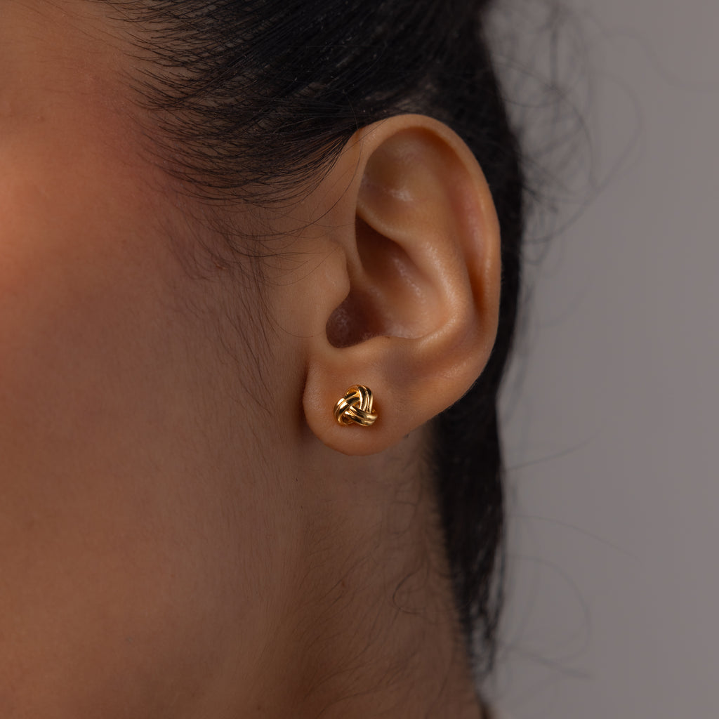 Close up of a model wearing our love knot studs in gold