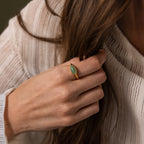 A hand adorned with the Marquise Jade Signet Ring touches long brown hair, paired with a cream textured top.