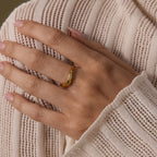 A hand with light pink nails wears the Zen Jade Curve Ring, its sculpted band and petite gem adding elegance against a cream knit sweater.