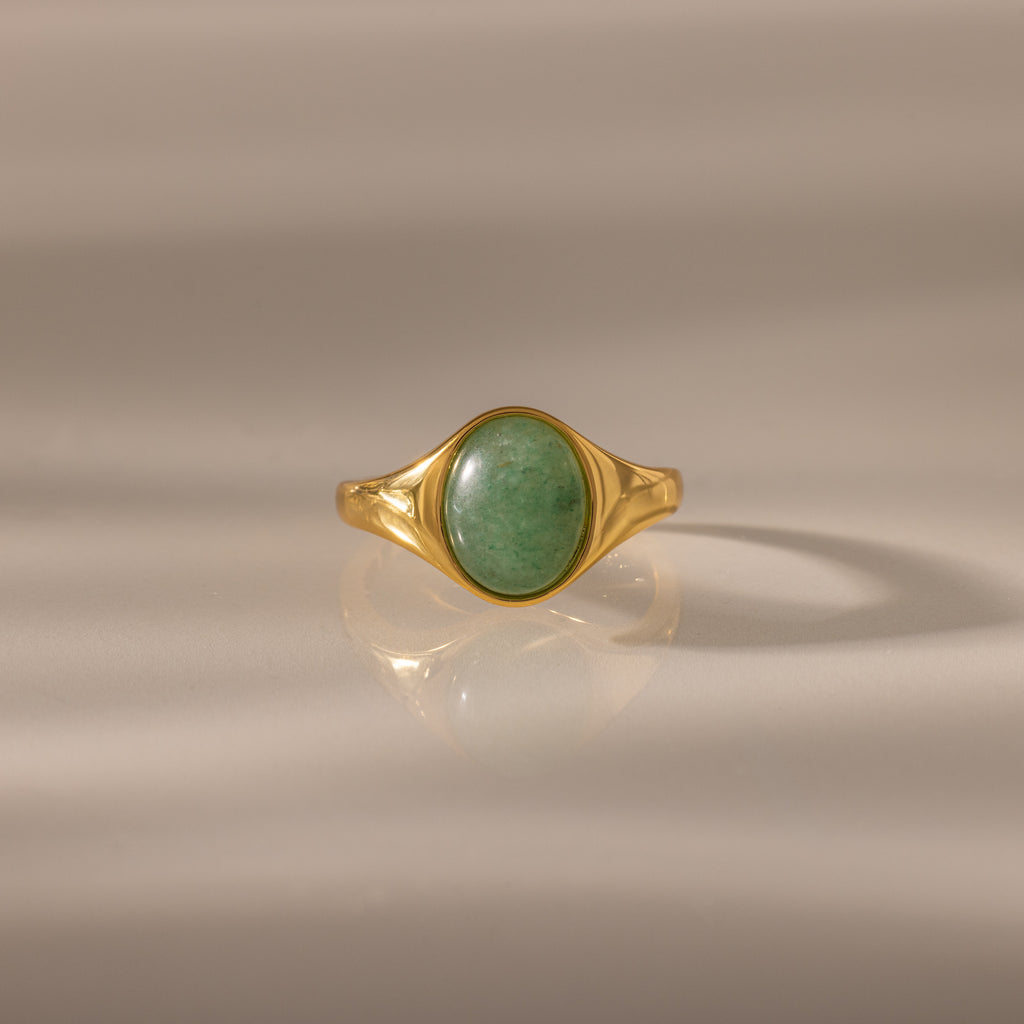 The Solace Jade Signet Ring features an oval-cut jade stone set at the center, showcased on a neutral background—a modern heirloom with timeless elegance.