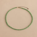 The Tiny Jade Choker Necklace in Silver features delicate green jade beads and a silver clasp with extender, shown on a beige background.